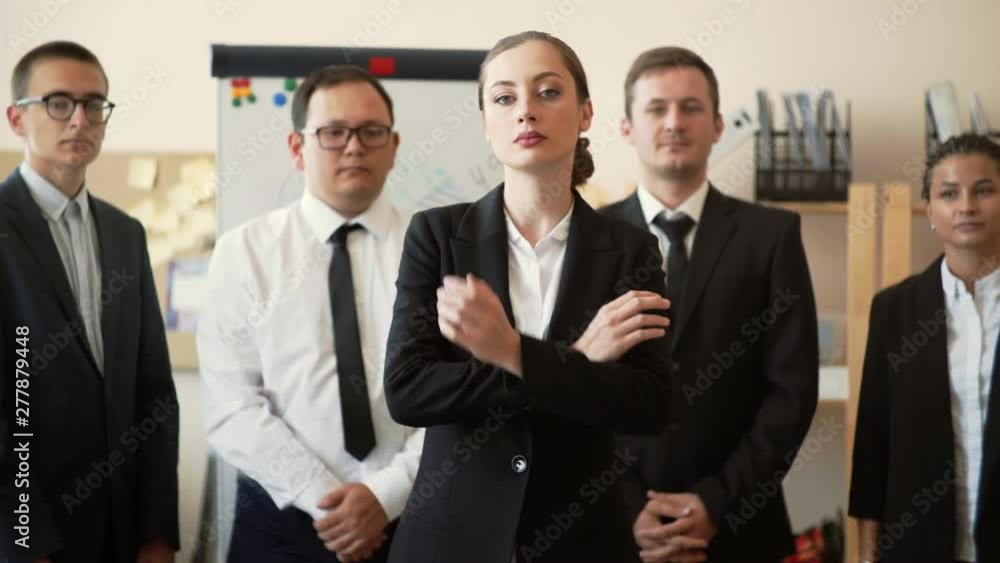 The girl owner of the business proudly stands in a jacket, behind her are her employees The girl owner of the business proudly stands in a jacket, behind her are her employees