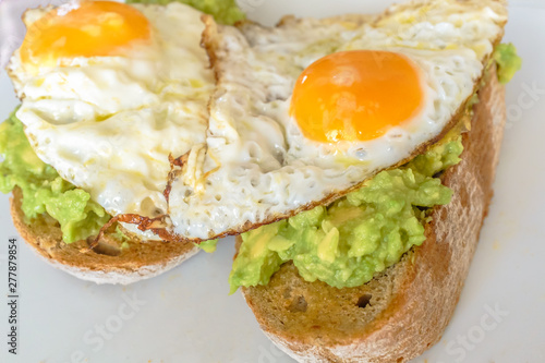 Two fried eggs on mashed avocado on thick wholemeal toast
