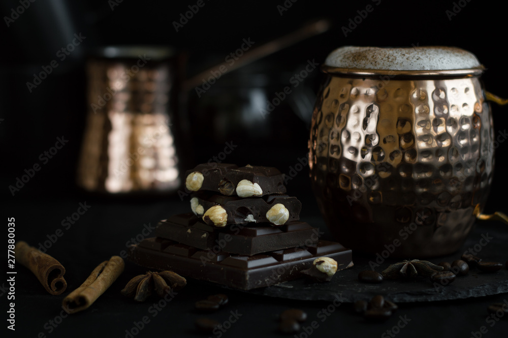 Dark chocolate with nuts and cappuccino coffee served in brass mug