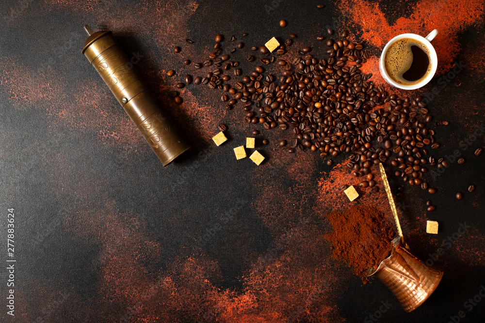 Turkish coffee concept. Copper coffee pot (Cezve), vintage coffee grinder, cup, coffee beans and sugar on a dark vintage background. Space for text. Top view