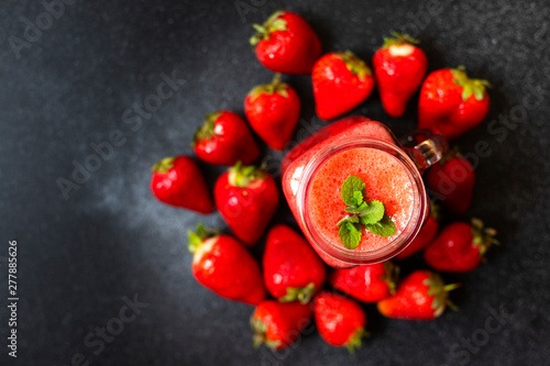 Strawberry smoothies or strawberries with ice in a jar. A refreshing summer drink. Black background. Top view. Copy space