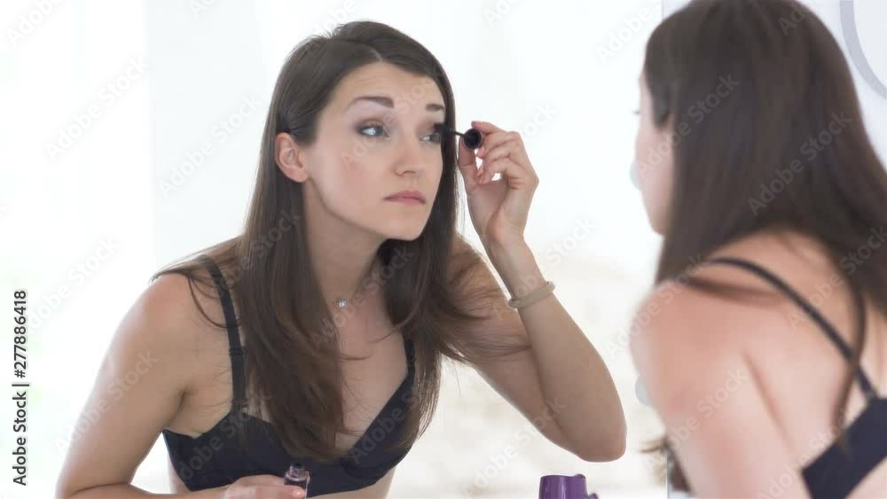4K. Young beautiful sexy woman model in lingerie do make up. Reflection in mirror, face close up 4K. Young beautiful sexy woman model in lingerie do make up. Reflection in mirror, face close up