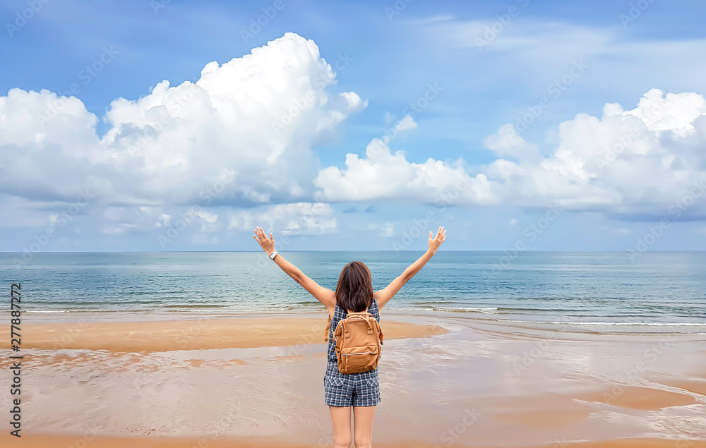 Women raise their arms and shoulder backpack on the beach background sea and sky at Chanthaburi in Thailand. Women raise their arms and shoulder backpack on the beach background sea and sky at Chanthaburi in Thailand.
