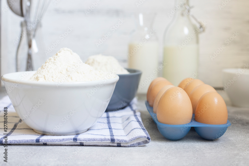 Ingredients for the dough, baking ingredients on a white background. Eggs, milk, flour and wire whisk. Front view. Baking concept. Space for text Ingredients for the dough, baking ingredients on a white background. Eggs, milk, flour and wire whisk. Front view. Baking concept. Space for text