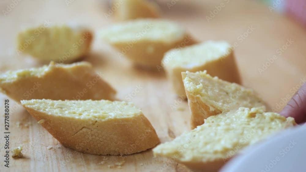 Kid's hands spreading garlic butter cream on sliced french bread. Kid's hands spreading garlic butter cream on sliced french bread.