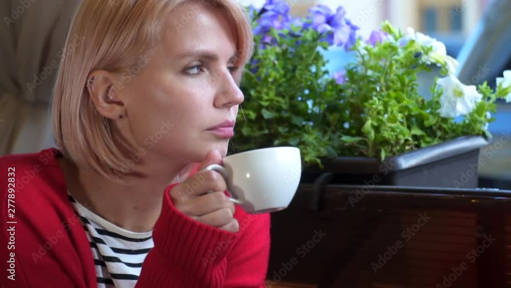Attractive woman with blue eyes drinking coffee enjoying her morning coffee. Smiling happy caucasian girl looking at camera Attractive woman with blue eyes drinking coffee enjoying her morning coffee. Smiling happy caucasian girl looking at camera