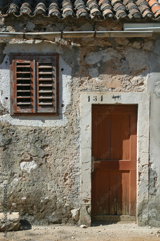 Wooden door and window on stone wall, building facade, Pag, Croatia