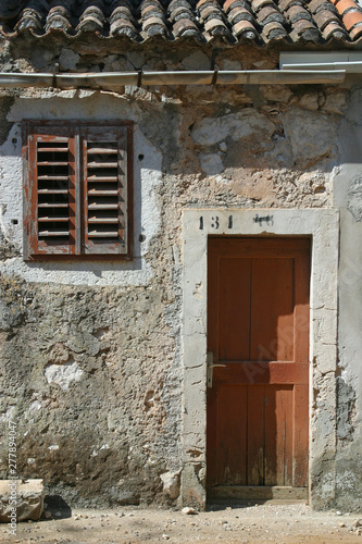 Wooden door and window on stone wall, building facade, Pag, Croatia