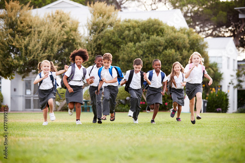 Excited Elementary School Pupils Wearing Uniform Running Across Field At Break Time © Monkey Business