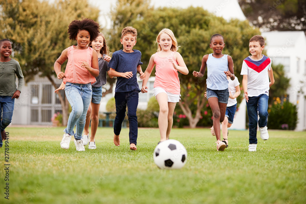 Obraz premium Group Of Children Playing Football With Friends In Park