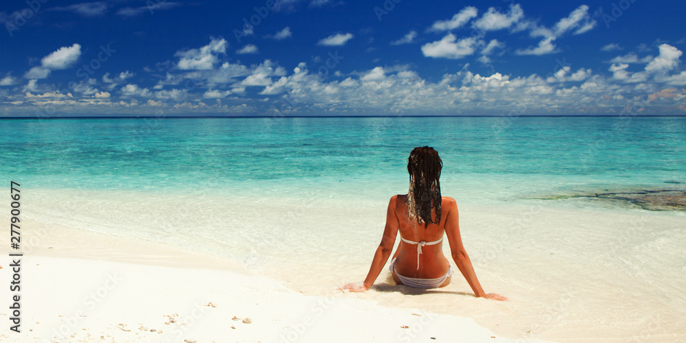 Obraz premium Young fashion woman relax on the beach. Happy lifestyle. White sand, blue sky and crystal sea of tropical beach. Vacation at Paradise. Ocean beach relax, travel to islands