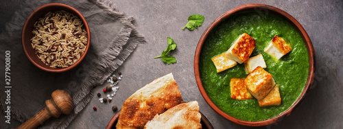 Palak paneer or Spinach and Cottage cheese curry,mortar with spices , naan, rice on a dark background, banner. Traditional Indian food. Top view, copy space. photo