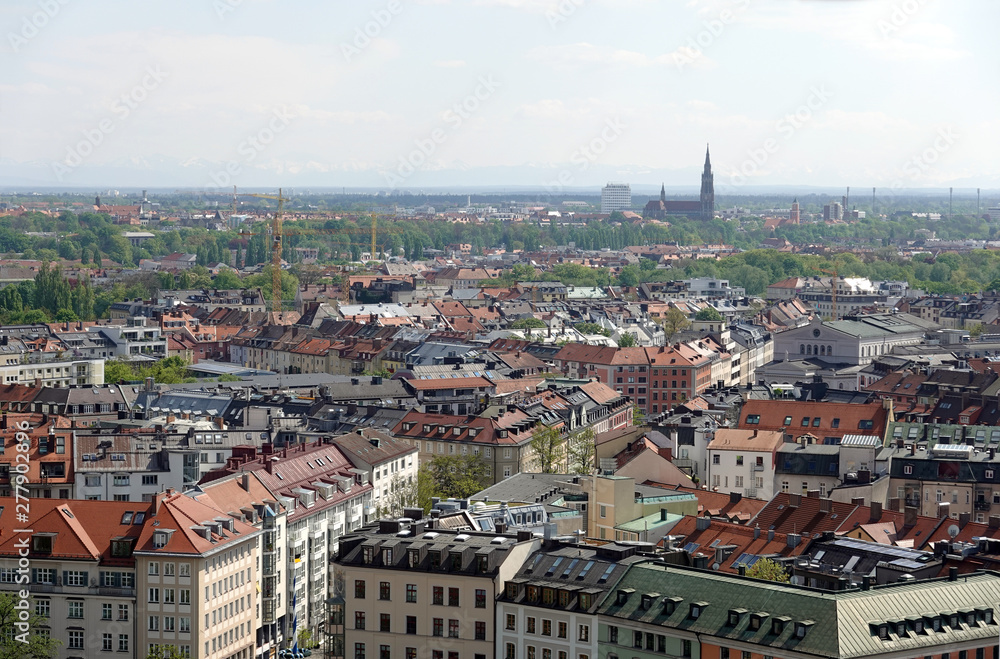 Bavarian capital Munich with many buildings roofs and Alps at far bird view in sunny summer day