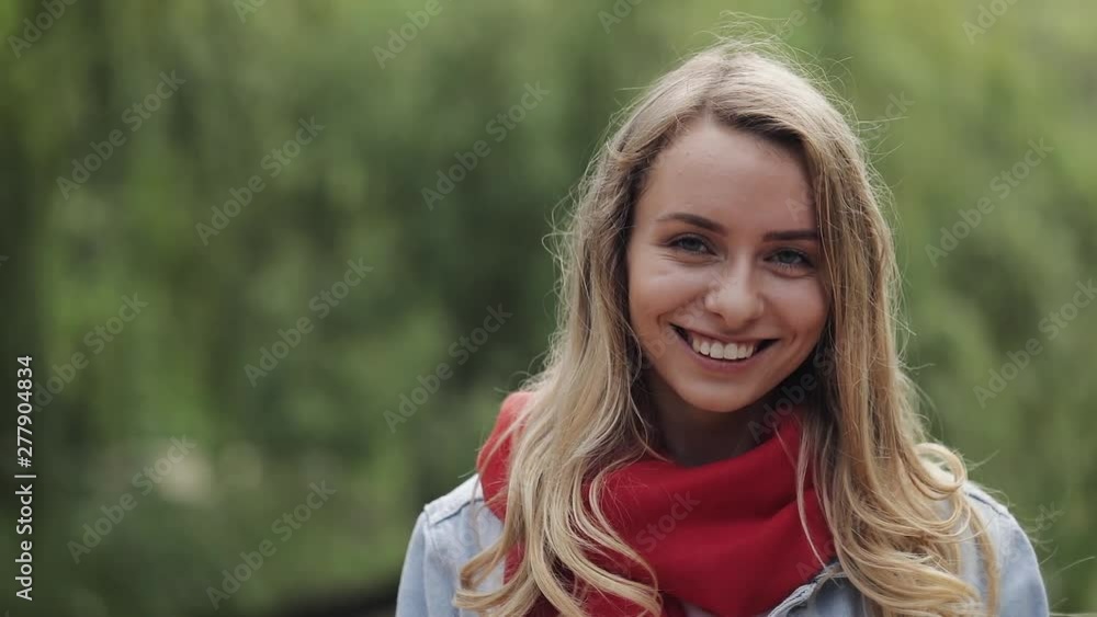 Portrait of young pretty woman laughing happy enjoying positive lifestyle wearing red scarf standing in the park. Smiling girl waving hand. Close up, lifestyle. Portrait of young pretty woman laughing happy enjoying positive lifestyle wearing red scarf standing in the park. Smiling girl waving hand. Close up, lifestyle.