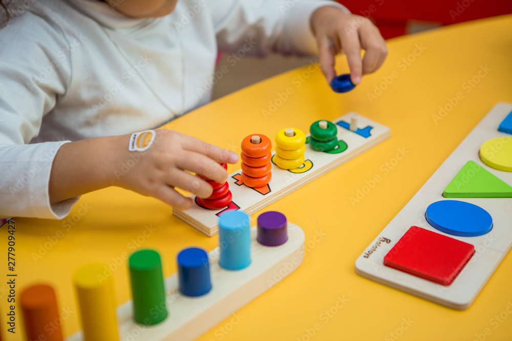 close-up of a child's hands collecting a multicolored wooden educational toy sorter close-up of a child's hands collecting a multicolored wooden educational toy sorter