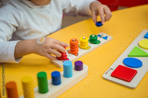 close-up of a child's hands collecting a multicolored wooden educational toy sorter