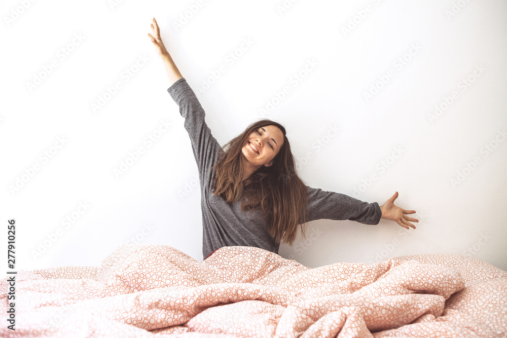 Φωτογραφία The girl woke up, stretched out her arms and rejoices at the coming of the morning