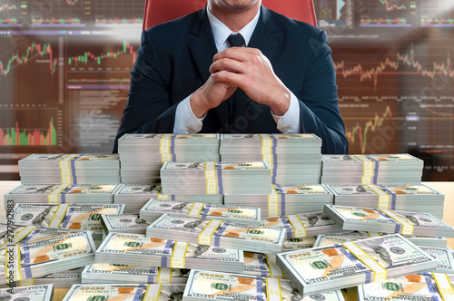 businessman sitting with pile of 100 dollar banknote photo