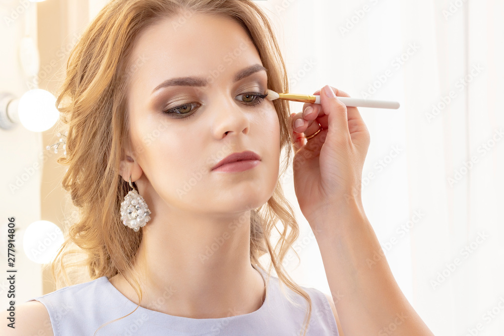 Makeup artist puts makeup on girl model. Brush applies shadows, concealer. beautiful girl model, portrait. Nude colors in makeup. wedding makeup, evening makeup. Makeup artist puts makeup on girl model. Brush applies shadows, concealer. beautiful girl model, portrait. Nude colors in makeup. wedding makeup, evening makeup.
