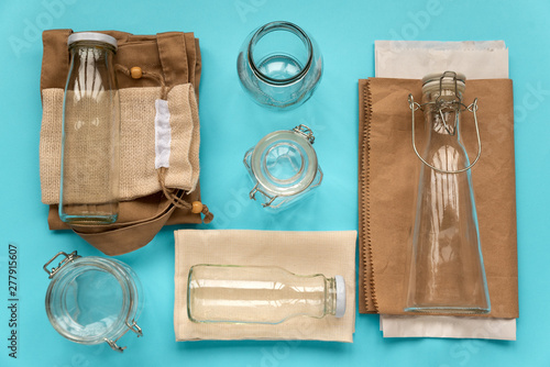 Set of textile eco bags, paper packages and glass jars lying on blue background. Eco friendly, reuse or zero waste concept. Top view. Flat lay
