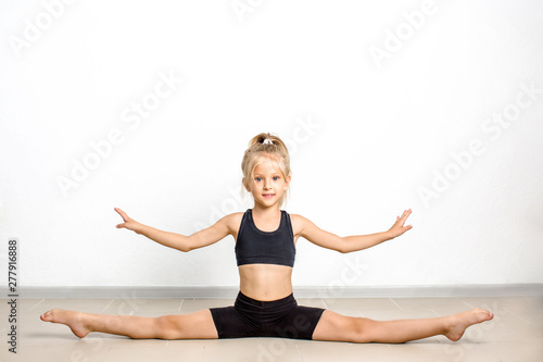 The girl is engaged in acrobatics, sports exercises for children, stretching muscles
