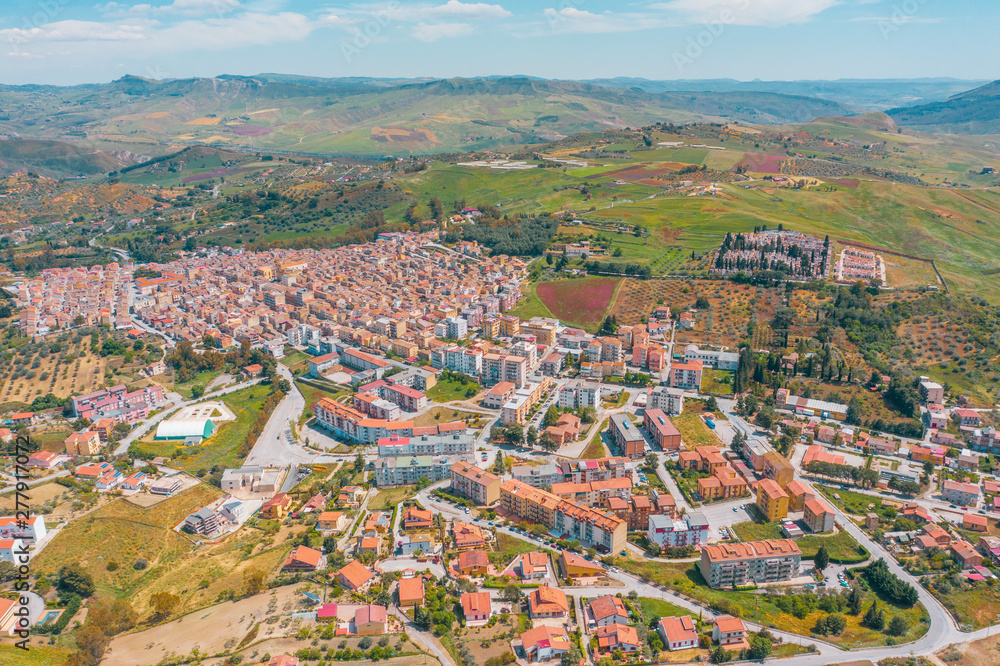 Small town in Italy among fields and hills, aerial view from a height.
