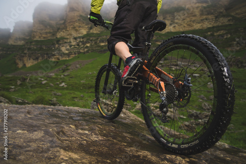 Rear view wide angle partly a man on a mountain bike travels on rocky terrain. The concept of a mountain bike and mtb downhill