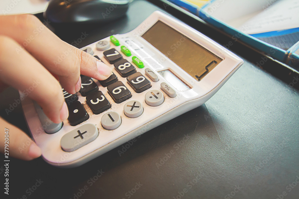 Employees are pressing the money calculator in the store. Employees are pressing the money calculator in the store.