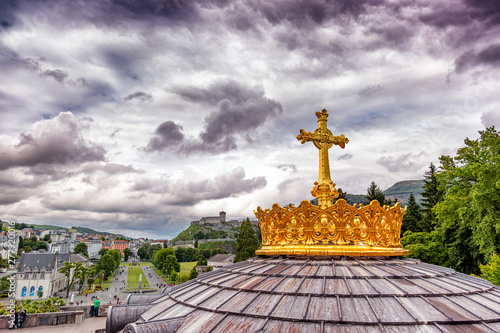 Christian gold cross on the roof of the Basilica of Our Lady of the Rosary in Lourdes, France