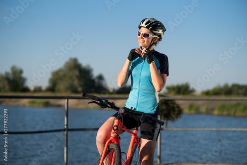Young woman on bike wearing a helmet at the sky background