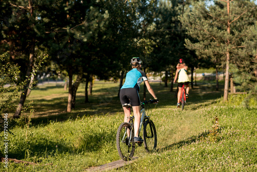 Two women friends riding bikes offroad at the forest