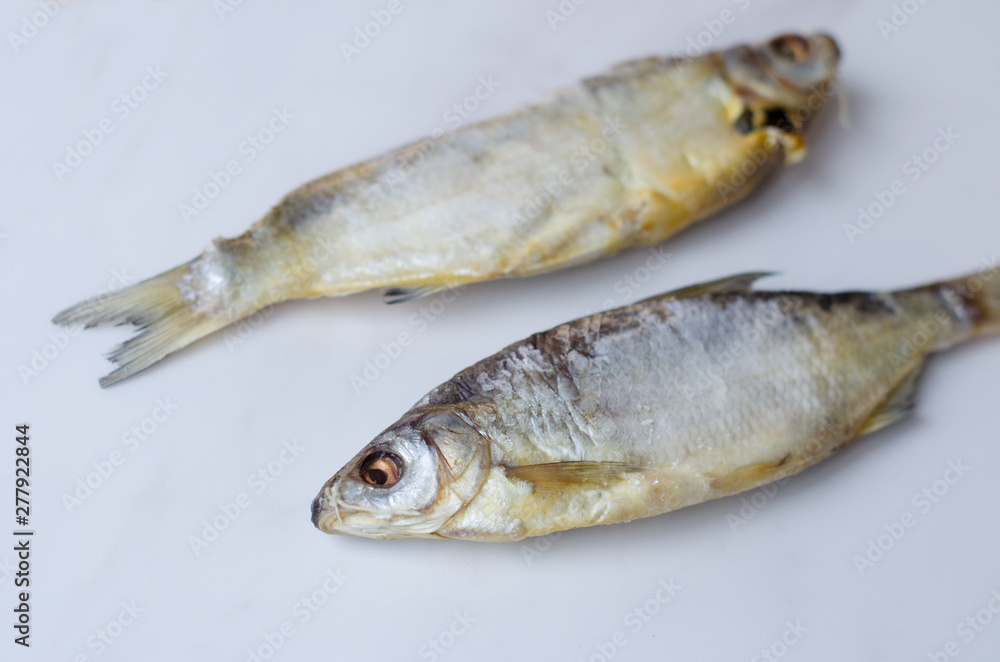 Dried fish on the table. Salty dry river fish on a white background top view Dried fish on the table. Salty dry river fish on a white background top view