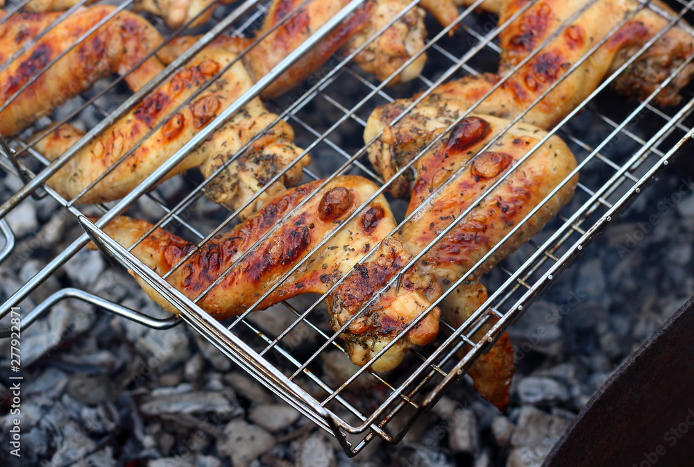 Cooking barbecue chicken wings on coals on grill. Concept background for a family summer picnic or weekend with friends. Selective focus, top view.