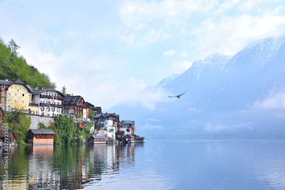 Obraz premium Amazing Hallstatt village with beautiful lake and alps mountains on background. Unesco heritage. Austria landmark with historic cathedral and wooden houses on the lake. Romantic view 
