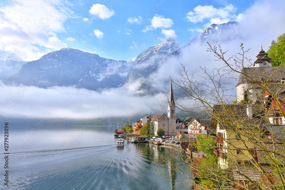 Naklejka premium Amazing Hallstatt village with beautiful lake and alps mountains on background. Unesco heritage. Austria landmark with historic cathedral and wooden houses on the lake. Romantic view 
