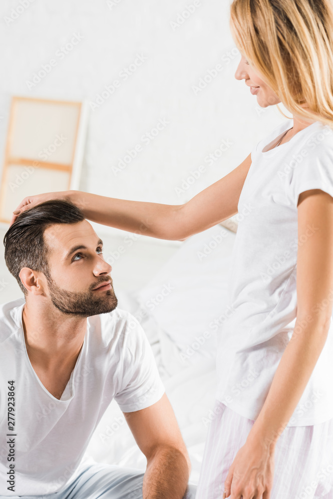 woman in pajamas stroking handsome man in bedroom woman in pajamas stroking handsome man in bedroom