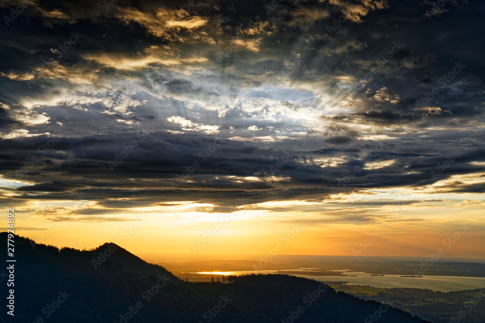 Beautiful sunset over lake Chiemsee with cloudy sky on Hochfelln mountain