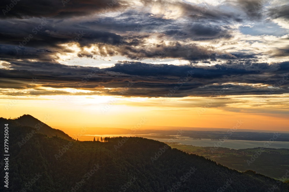 Beautiful sunset over Chiemsee lake with cloudy sky on Hochfelln mountain