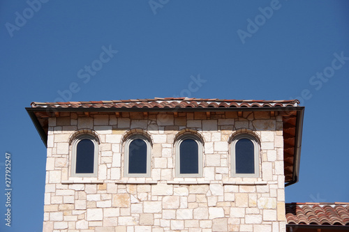 View of the tower-like top floor of a modern building in Spanish retro style under a deep blue sky photo