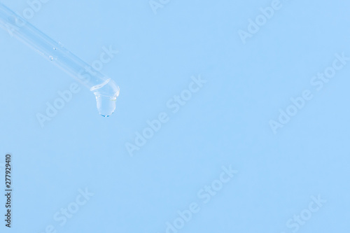 Serum for cosmetic procedures. Serum on a blue background. Cosmetic pipette with a drop. Minimalism. Close up