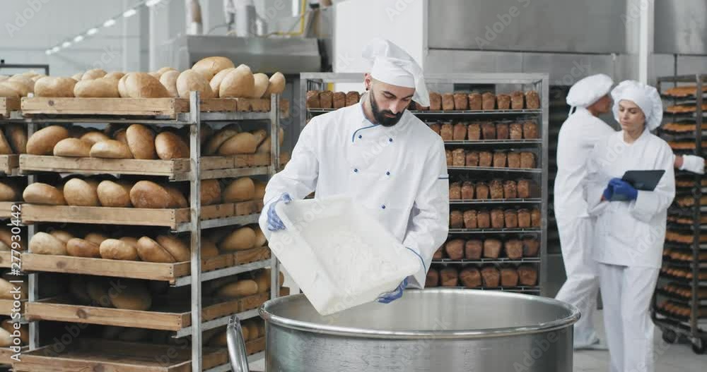 Bakery industry big chef in a special uniform preparing the dough add ...