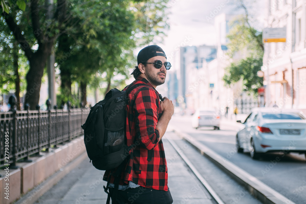 A man tourist walks through the streets with a backpack