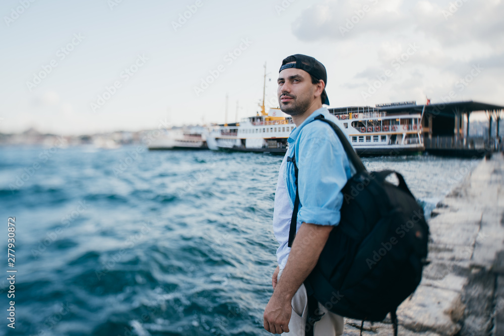 Portrait of a young man against the background of the sea, city, pier and ships. Portrait of a young man against the background of the sea, city, pier and ships.