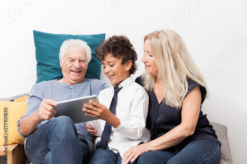 GRANDS PARENTS AVEC LEUR PETIT FILS REGARDANT UNE TABLETTE