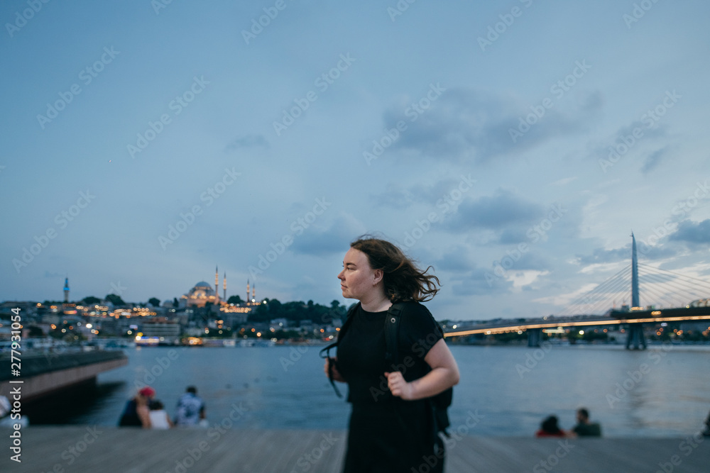 The girl at sunset on the waterfront on the background of the city