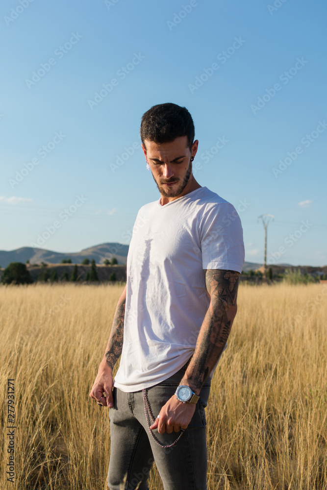 Attractive man with tattoos on his arms in a meadow Attractive man with tattoos on his arms in a meadow