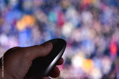 Male hand switches channels on tv remote at night