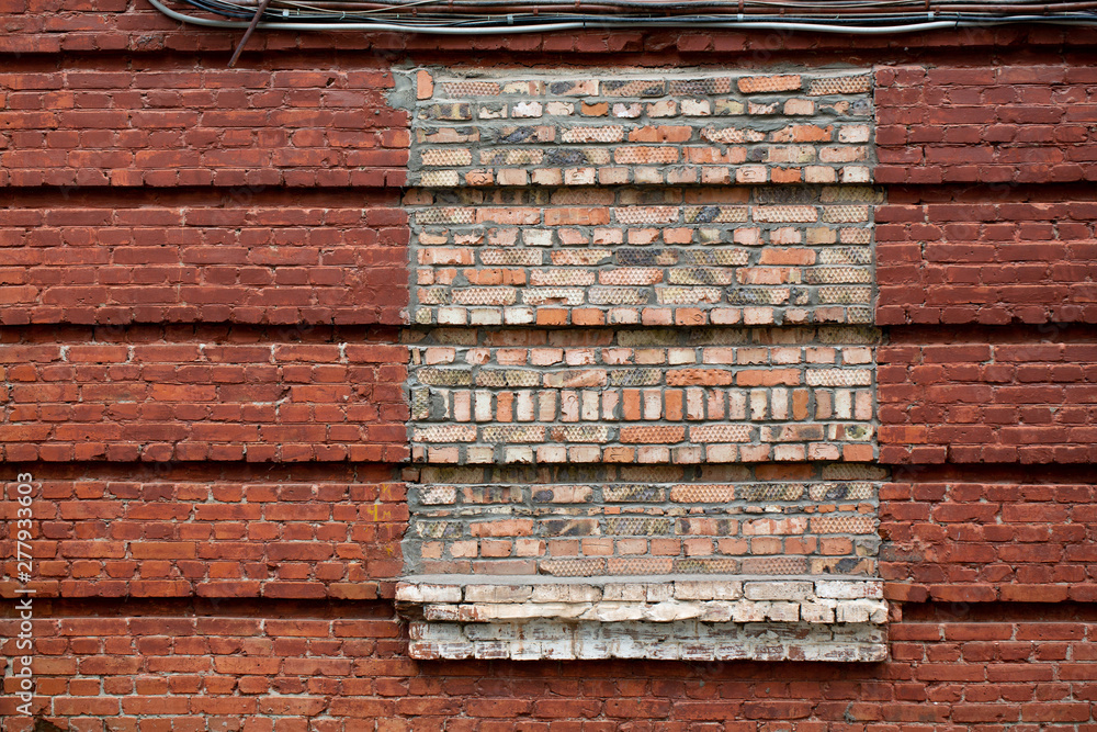 Red brick wall. The window is covered with bricks in the old house. Red brick wall. The window is covered with bricks in the old house.
