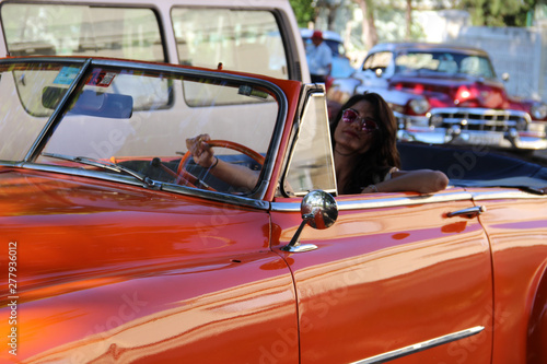girl driving old orange car in Havana, Cuba © Alohadunya