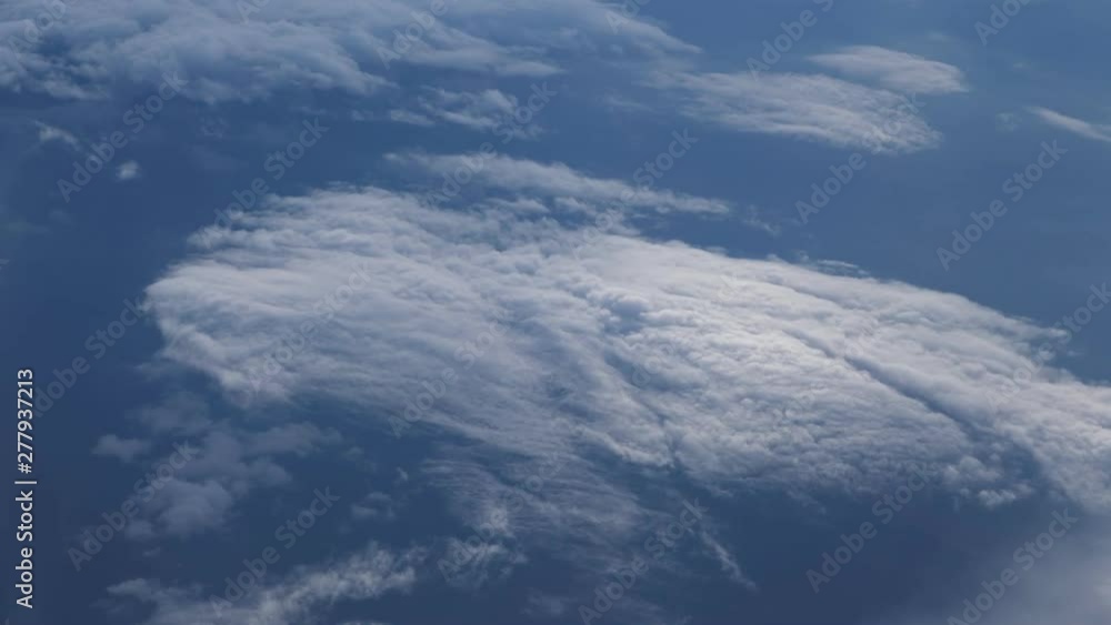 Aerial view from the airplane. Flying over the layer of clouds and looking on landscape through the clouds. Soft sunlight in sky. Aerial view from the airplane. Flying over the layer of clouds and looking on landscape through the clouds. Soft sunlight in sky.